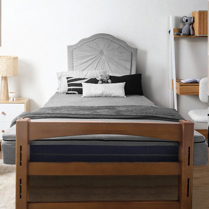 Cozy bedroom with wooden bed frame and gray bedding, featuring twin XL mattress topper for college comfort